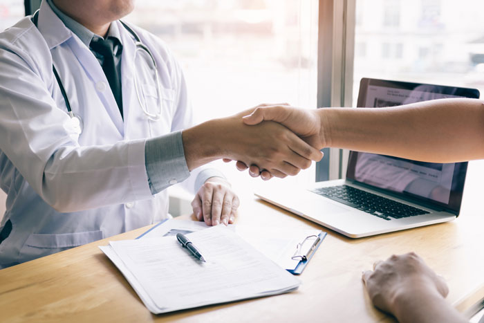 dentist shaking a patient's hand on a contract